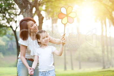 Mother and children playing windmill in nature park.