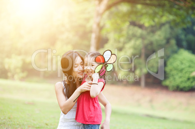 Mother and daughter playing windmill in nature park.