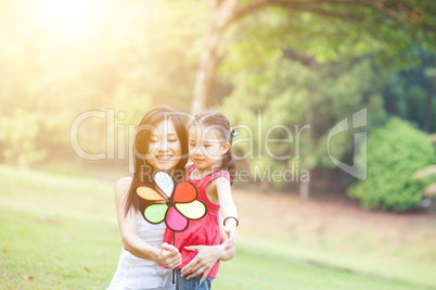 Mother and daughter playing windmill in the park.