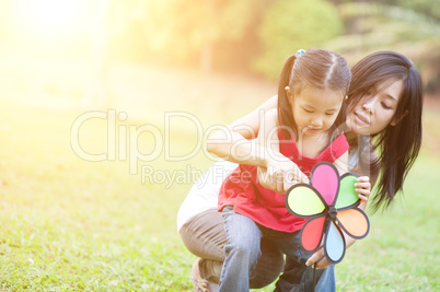 Asian mother and daughter playing windmill at outdoors.