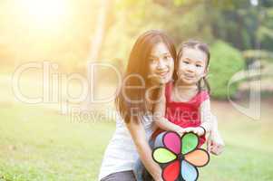Asian mother and daughter playing windmill at outdoor park.