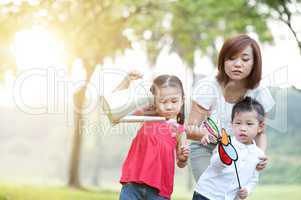 Asian mother and children playing at outdoor park.