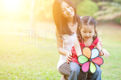 Mother and daughter playing windmill at outdoor park.