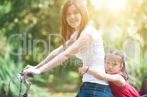 Mother and daughter biking outdoor.