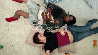 Happy mixed family with child lying on the floor
