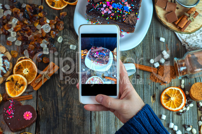 White smartphone in a woman's hand takes a piece of cake and swe