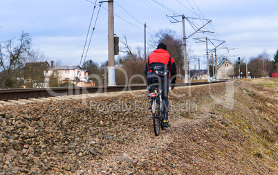 a cyclist rides along the tracks of the railroad, the cyclist rides along a rail