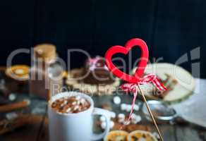 wooden heart on a stick on a background of cups with drink choco