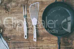 Empty black cast-iron frying pan with vintage kitchen items on a