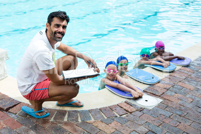 Male instructor with little swimmers at poolside