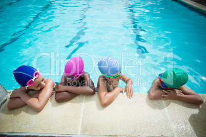 Little swimmers talking while leaning at poolside