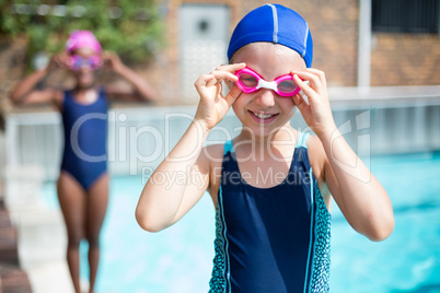 Portrait of smiling girl wearing goggles at poolside