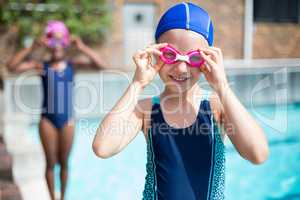 Portrait of smiling girl wearing goggles at poolside