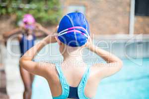 Girls adjusting swimming goggles at poolside