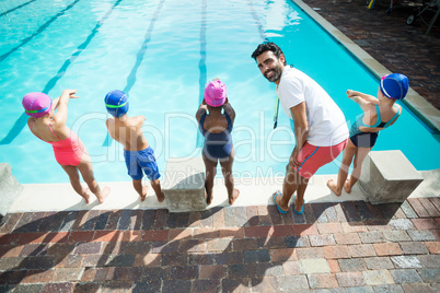 Instructor preparing little swimmers to jump into swimming pool
