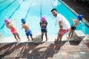 Instructor preparing little swimmers to jump into swimming pool