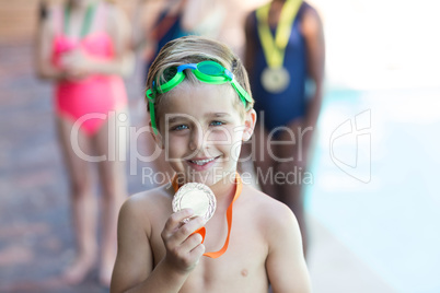 Little boy showing medal at poolside
