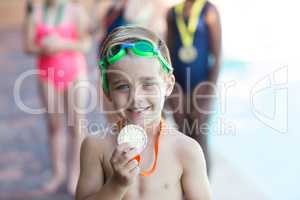 Little boy showing medal at poolside