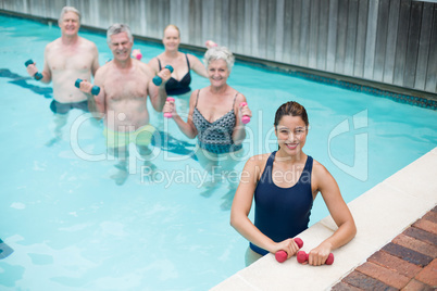 Female trainer with senior swimmers standing in pool