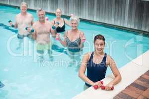 Female trainer with senior swimmers standing in pool
