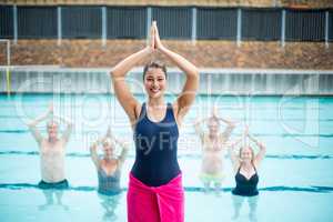 Female yoga instructor assisting senior swimmers at poolside