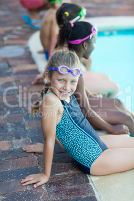 Cute girl sitting with friends at poolside