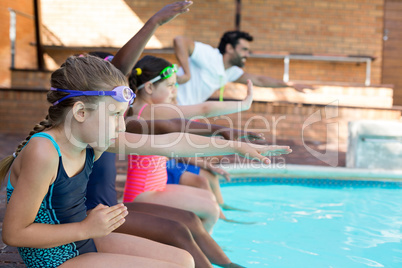 Male instructor assisting girls at poolside Male instructor assisting girls at poolside