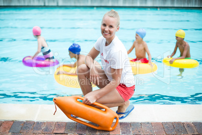Portrait of female lifeguard holding rescue can at poolside