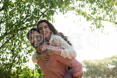 Happy man piggybacking woman at park