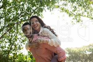 Happy man piggybacking woman at park