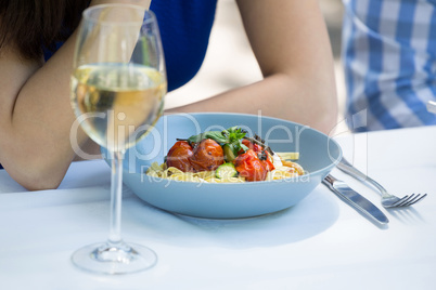 Cropped image of couple with food and wineglass on table