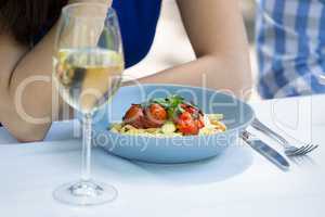 Cropped image of couple with food and wineglass on table