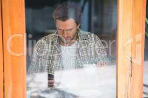 Man using mobile phone in cafe seen through window