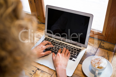 High angle view of woman using laptop in coffee shop