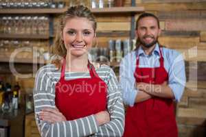 Smiling female barista with male coworker in coffee shop