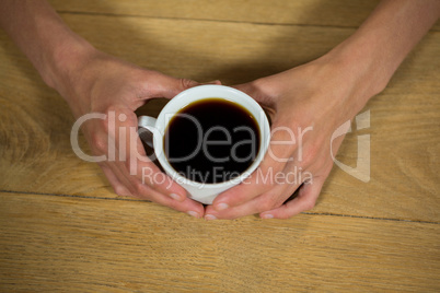Man holding coffee cup at table in cafeteria