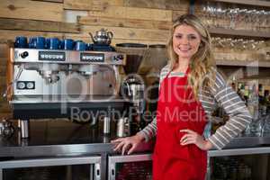 Portrait of smiling woman standing by coffee machine in cafeteria