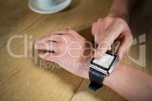 Man using smart watch at table in coffee shop
