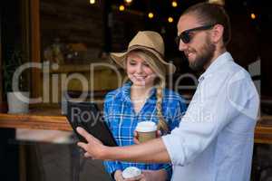 Smiling couple using digital tablet in coffee shop