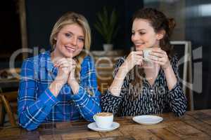 Portrait of smiling woman with friend having coffee in cafe