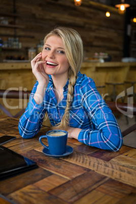 Portrait of cheerful woman sitting at table in coffee shop