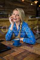 Portrait of cheerful woman sitting at table in coffee shop