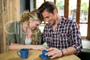Smiling couple sitting head to head at table in coffee shop