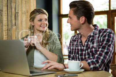 Man using laptop while looking at woman in coffee shop