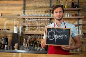 Barista holding open signboard in coffee shop