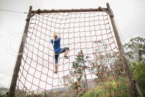 Woman climbing a net during obstacle course