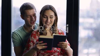 Sweet young couple reading a book together at home