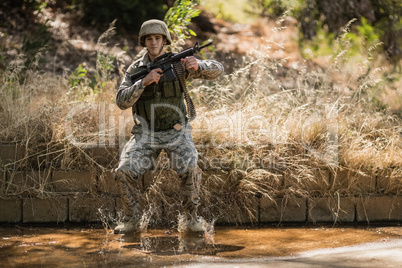 Military soldier with rifle jumping in water