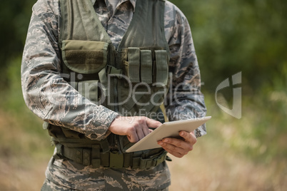 Mid section of military soldier using digital tablet