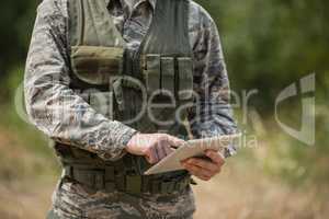 Mid section of military soldier using digital tablet